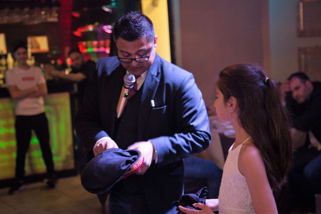 Magician performing a close-up magic trick with a young guest