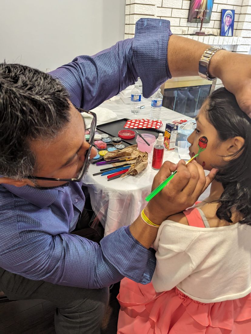 Face painter painting a rose design on a young guest