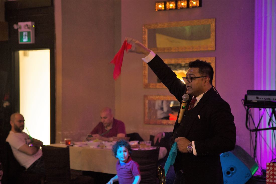 Illusionist performing a stage magic and mentalism show under dramatic lighting